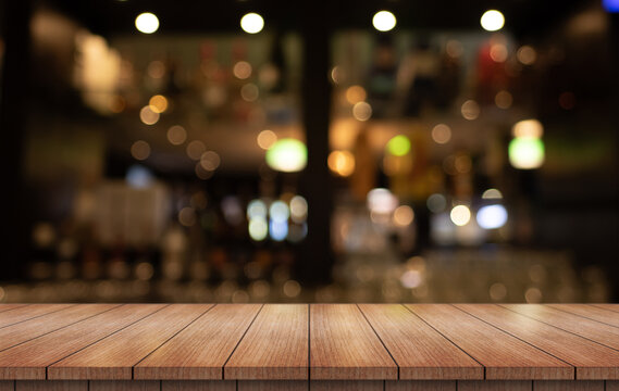 Empty wooden table top with lights bokeh on blur restaurant background.