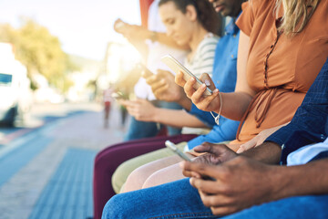 Hands, phone and people waiting at bus stop in city for commute or public transport closeup. App, contact and social media with passenger group on sidewalk outdoor together for mobile communication