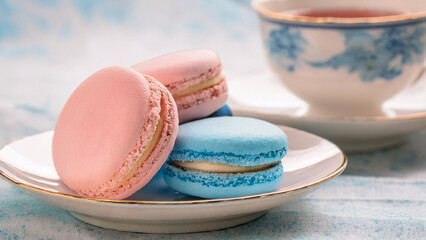 Pink and Blue Macarons on a Plate with Teacup in Background