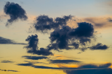 Bizarre dark clouds in yellow sky at sunset