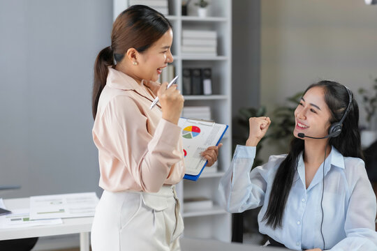 Two happy businesswomen celebrating a successful business plan while analyzing financial charts in the office