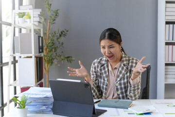 Businesswoman is getting angry and screaming while working on a tablet in her office, she is very overwhelmed by work