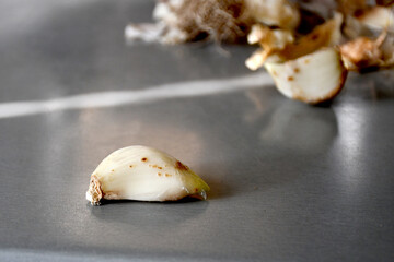 Peeled garlic clove with brown sores on a blurred background. Selective focus. Damaged garlic, spoiled crops, unsuitable for eating and planting