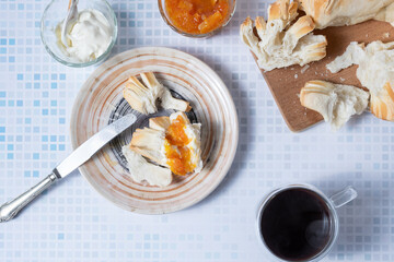 Top view of a breakfast with bread, jam, cream cheese and coffee.