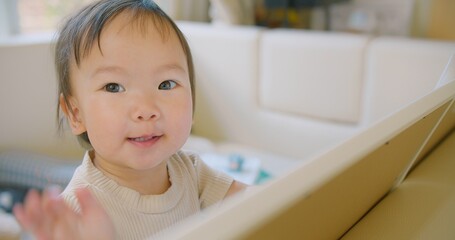 Fototapeta premium A cute Asian toddler is intently looking at a tablet, showcasing curiosity and concentration. The child is indoors cozy environment emphasize a sense of warmth and comfort.