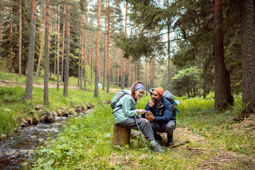 Father and daughter checking smartphone during forest hike