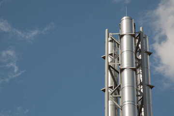 Stainless steel pipe for flue gases from the boiler room besides sky view.