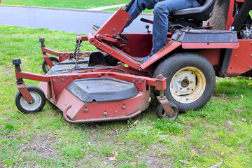 Obraz premium An employee of city mows grass in park with lawn mower tractor during landscaping operations
