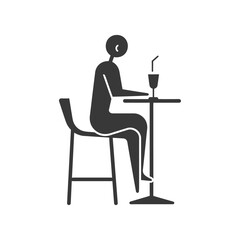 Silhouette of a person sitting at a table with a drink