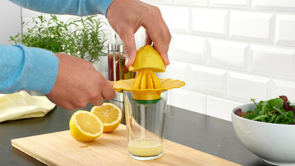 Closeup of a person squeezing lemons in a glass.