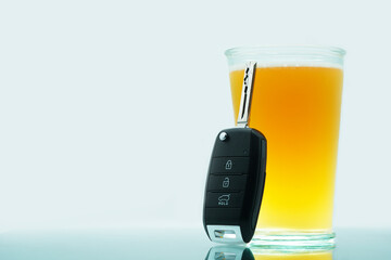 Drunk driving concept. Car keys resting on a glass of wheat beer. White background, space to add your description, text, logo