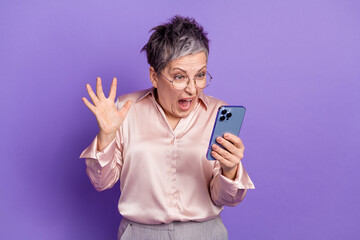 Photo portrait of attractive retired woman hold device read horrible news dressed stylish satin clothes isolated on violet color background
