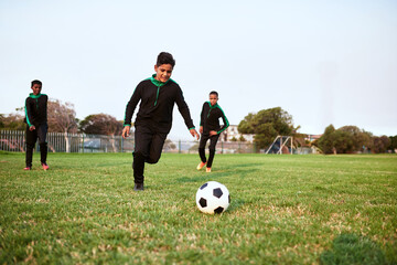 Boys, soccer and playing with ball on grass field for sports, game or training routine with team in...