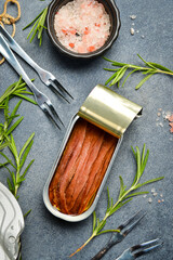 Salted anchovies in oil in a tin can. Canned food in aluminum cans. On a gray concrete background.