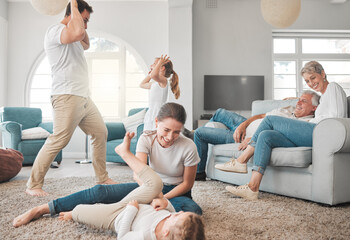 Parents, children and playing on floor in living room for funny games, joke and support on weekend. Happy, father and mother bonding with kids on carpet at home for humor, love and laughing together