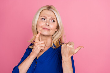 Photo portrait of attractive retired woman look point skeptical empty space dressed stylish blue clothes isolated on pink color background