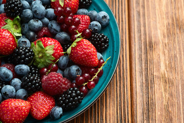 Mix of ripe colorful berries in bowl photography . Blueberry , strawberry , raspberry , blackberry and red currant . Top view