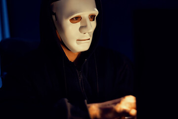 White criminal anonymous mask installing coding password encryption by programming hack, trying to make insecure thorough privacy taking massive database on computer for ransom to company. Pecuniary.