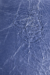 Raindrops Creating Ripples in Calm Water Surface on a Clear Day