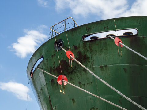 Red ocean ship rat guards on the mooring lines of a vessel to keep rodents front getting on and off.