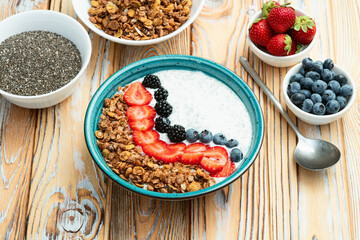 Healthy breakfast . Yogurt with berries ( strawberry , raspberry , blueberry , blackberry ) , granola and chia seeds . Top view