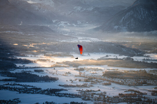 Man paragliding over an alpine winter landscape at sunset, Salzburg, Austria