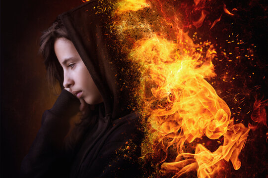 Conceptual portrait of a sad teenage girl wearing a burning hoodie