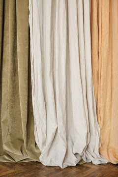 Close-up of floor length Olive, light grey and beige curtains hanging side by side