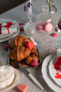 Overhead view of an Elegant romantic table setting for two with gifts, croissants, macrons, sweet treats and heart shaped decorations