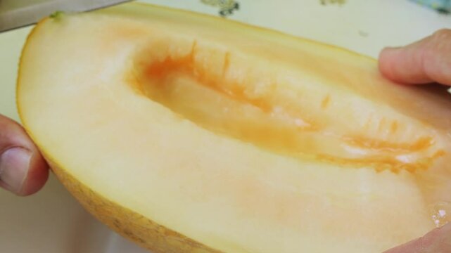 Long pieces are cut off from a melon cut lengthwise with a knife