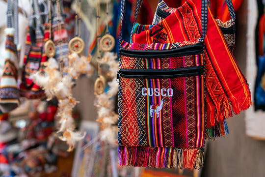 Close-up of colorful handbags with text saying Cusco (Cuzco), Pisac market, Pisac, Sacred Valley, Urubamba Province, Cusco (Cuzco) Region, Peru