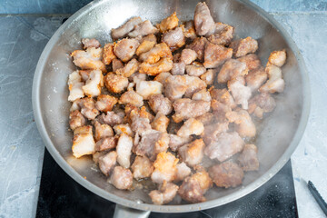 Pieces of pork are fried in a pan. Recipe.