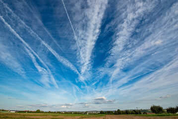 Kondensstreifenam blauen, leicht bewölkten Himmel laufen im Fluchtpunkt zusammen