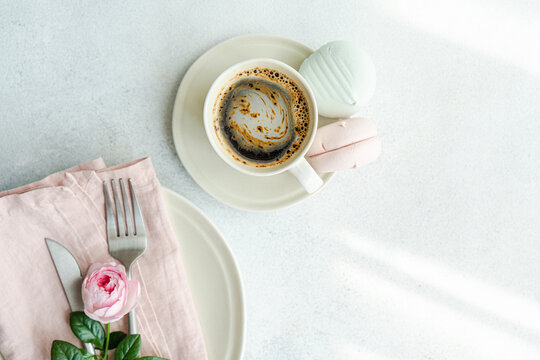 Overhead view of a place setting decorated with a pink rose and a cup of coffee with Zefir confectionery