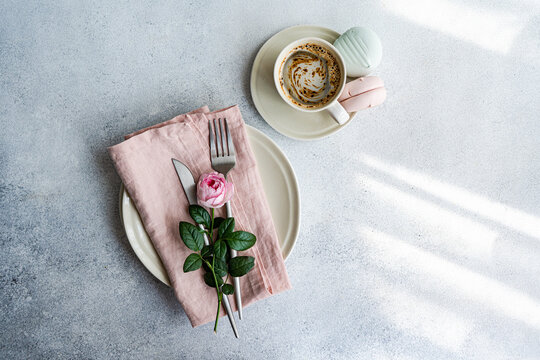 Overhead view of a place setting decorated with a pink rose and a cup of coffee with Zefir confectionery