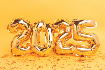 2025 - golden shiny air balloons with confetti. New Year monochrome composition.