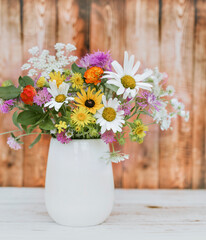 Beautiful Wild Summer Flowers in a Small Vase on wooden background 