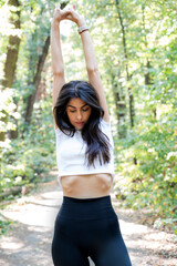 Beautiful woman stretching in the summer city park 