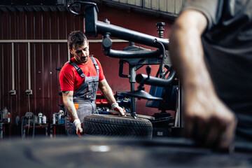 Experienced mechanic working on tire changer machine removing damaged tire from the wheel.