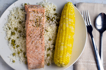 baked salmon served with rice and corn