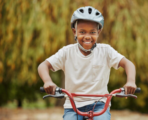 Black child, portrait and bicycle with helmet for ride, acitivty or outdoor exercise in nature. Young African, little boy or happy kid with smile on bike for safety, adventure or trip in neighborhood