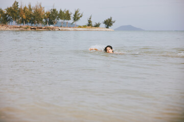 Smiling Asian Man Enjoying Tropical Vacation, Swimming in Blue Ocean