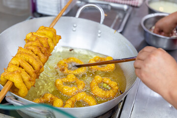 A person is frying picarones in a pan