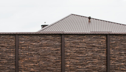 A new fence on the background of the roof of a private house