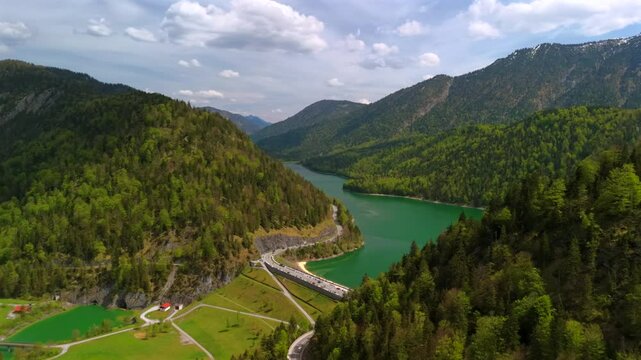 Staudamm am Sylvensteinspeichersee und der Sylvensteinsee in Bayern, Deutschland Lenggries. Dam and observation deck on a large reservoir Sylvensteinsee in Bavaria, Germany on sunny spring day. 