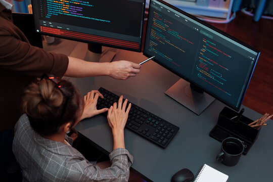 Top view of IT developers discussing with point to intelligent website development coder system running data online two screens information technology at neon light room at modern office. Infobahn.