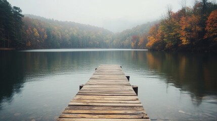 Naklejka premium Calm autumn lake view with a wooden dock under clear blue skies