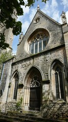 Fototapeta premium A beautifully designed gothic church stands proudly, surrounded by greenery and bathed in sunlight