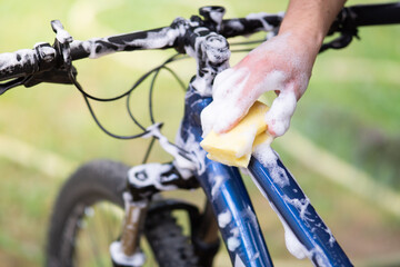 Man washing bicycle with sponge and soap, close up