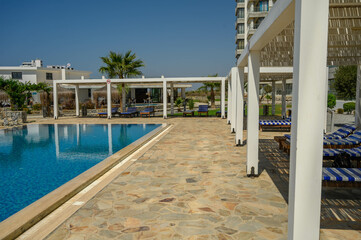 Modern luxury house with sunbeds dining area near outdoor swimming pool in sunny backyard